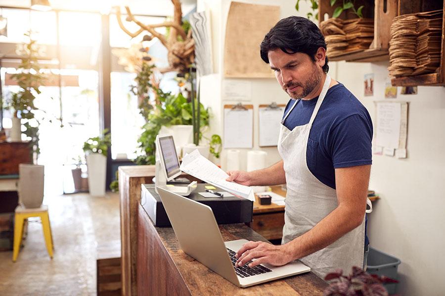 Resengo - man works on laptop in his restaurant.